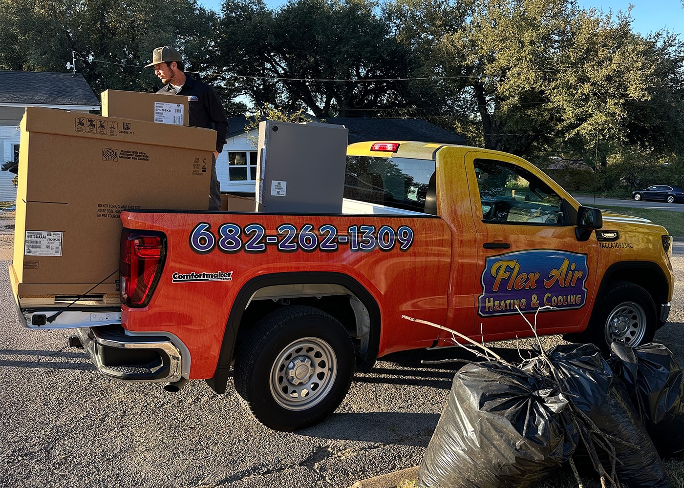 Flex Air Heating and Cooling technician loading new HVAC equipment into service truck bed